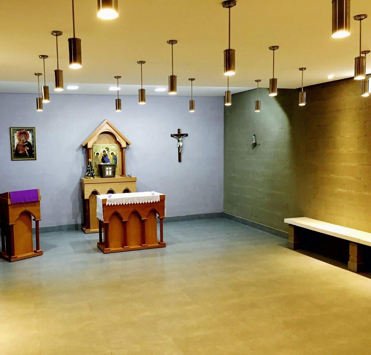 Interior da capela com altar, crucifixo e luminárias